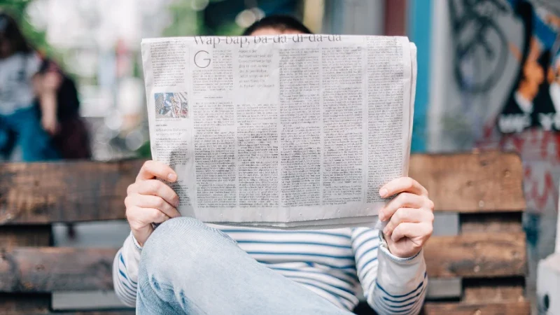 10. Leverage Traditional Media for Wider Reach Man sitting on bench reading newspaper